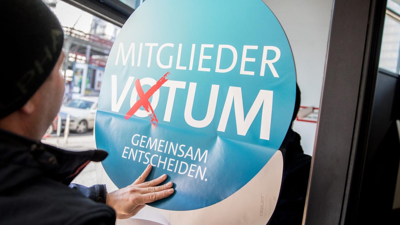 Ein Helfer klebt ein Logo für das SPD-Mitgliedervotum: Die Partei ist in Befürworter und Gegner der großen Koalition gespalten.