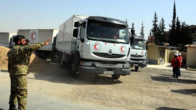 Ein syrischer Soldat weist einen Lkw mit Hilfsgütern in Richtung des Stadtteils Duma im umkämpften Gebiet Ost-Ghuta. Ein syrischer Soldat weist einen Lkw mit Hilfsgütern in Richtung des Stadtteils Duma im umkämpften Gebiet Ost-Ghuta.