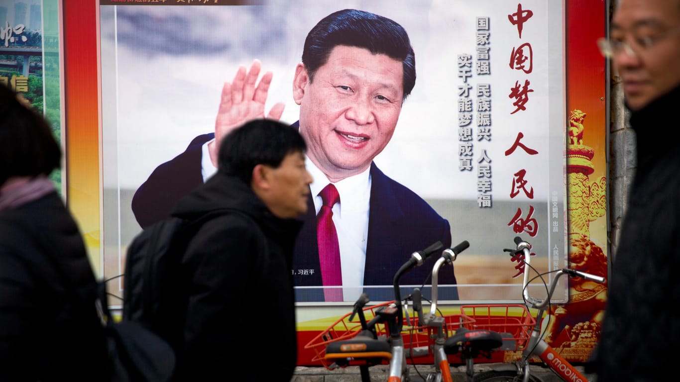 Passanten vor einem Plakat mit dem Abbild von Xi Jinping in Peking.