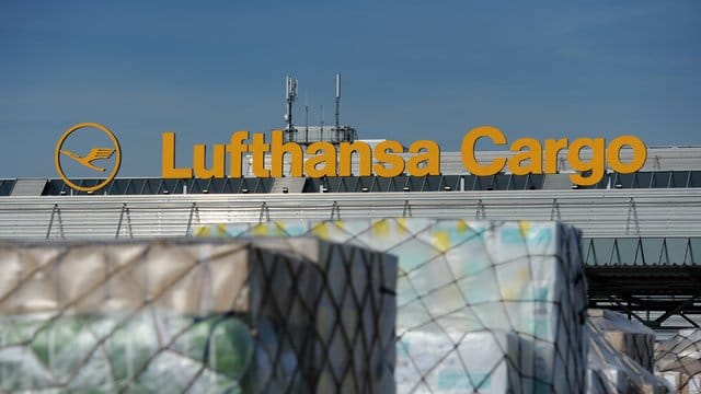 Paletten mit verpackter Fracht vor einer Halle der Lufthansa Cargo.