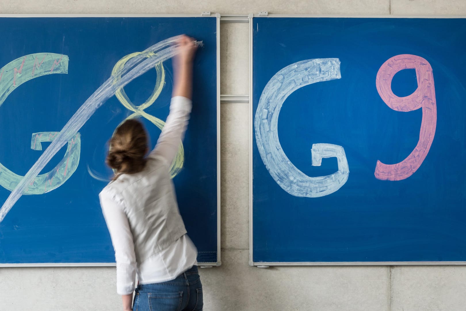 Eine Schülerin der Oberstufe streicht an einem Gymnasium den Schriftzug "G8" an einer Tafel durch, daneben lässt sie «G9» unberührt: Die NRW-Landesregierung hat die Rückkehr zum neunjährigen Gymnasium beschlossen.