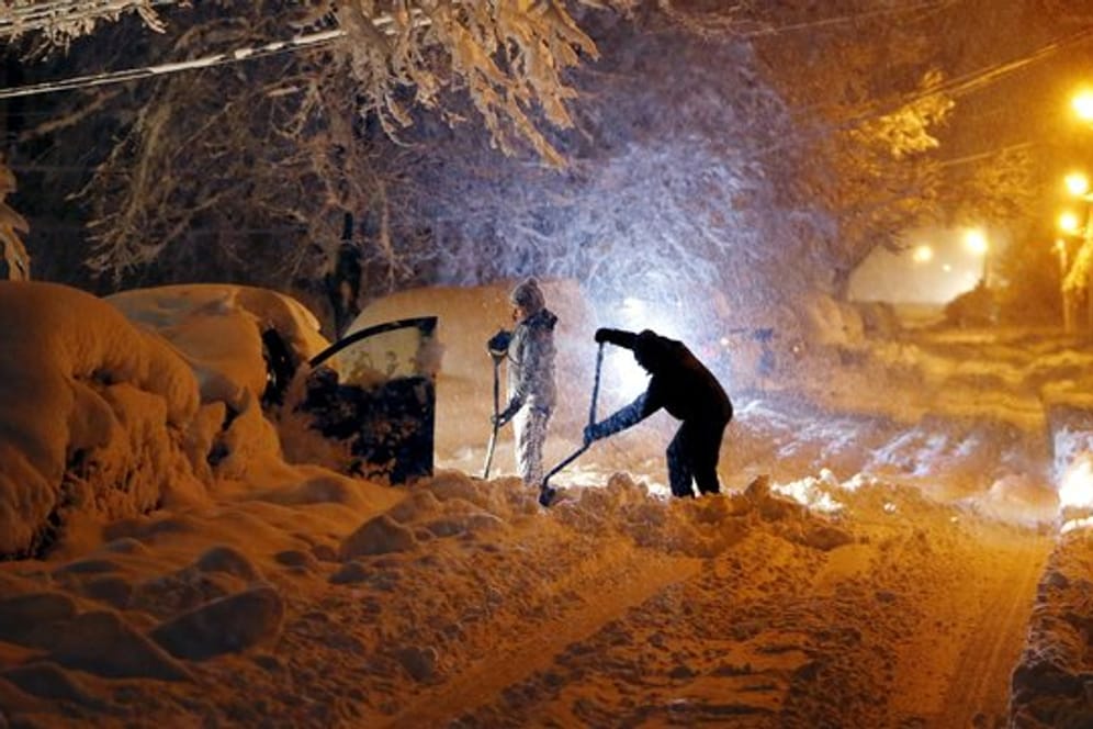 In Morristown im US-Bundesstaat New Jersey versuchen Anwohner ihr Auto vom Schnee zu befreien.
