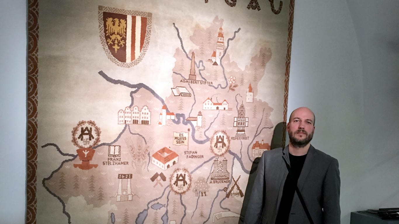 Kurator Peter März steht vor einem 1940 gewebtem Wandteppich, der die Heimat Adolf Hitlers (Oberösterreich) als "Oberdonau" im Schlossmuseum in Linz (Österreich) zeigt.