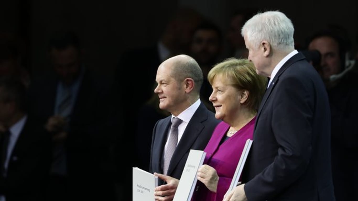 Bundeskanzlerin Merkel, CSU-Chef Horst Seehofer (r) und der kommissarische SPD-Vorsitzende Olaf Scholz präsentieren den unterzeichneten Koalitionsvertrag.