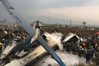 Rettungskräfte stehen auf dem Flughafen von Kathmandu neben der abgestürzten Maschine.