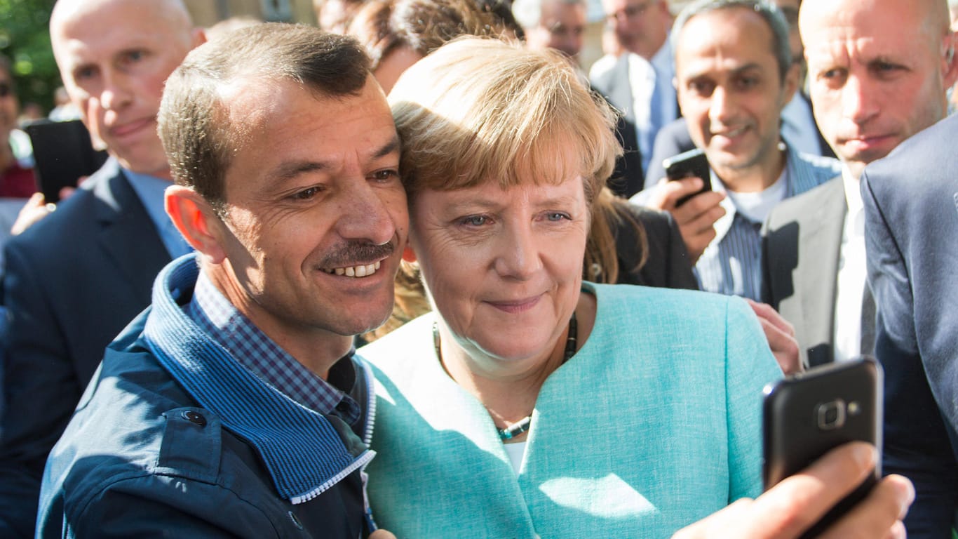 Selfie mit Flüchtling: Als 2015 Hunderttausende Schutzsuchende nach Europa kommen, stellt sich Merkel nicht dem Lauf der Dinge in den Weg.