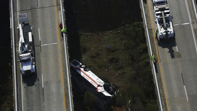 Rettungskräfte schauen auf einen verunglückten Bus hinab. Rettungskräfte schauen auf einen verunglückten Bus hinab.