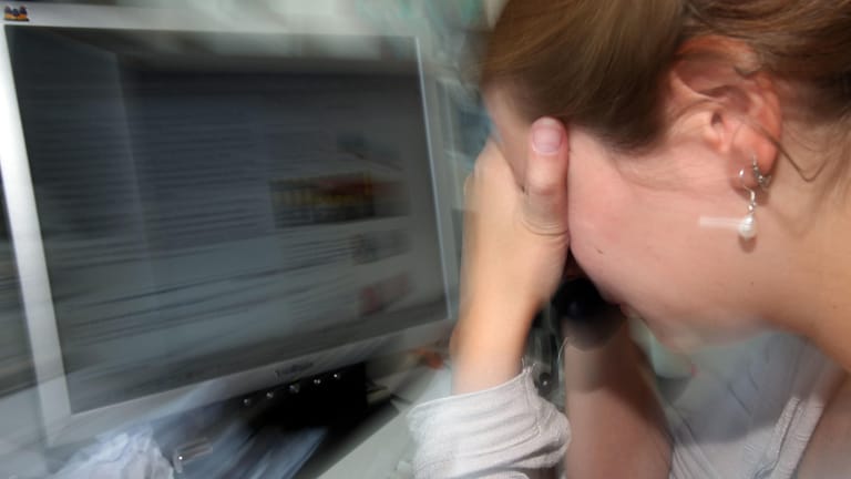 Eine Frau legt an ihrem Arbeitsplatz den Kopf in die Hände: Grund können Augenprobleme wegen des Computerbildschirms sein.