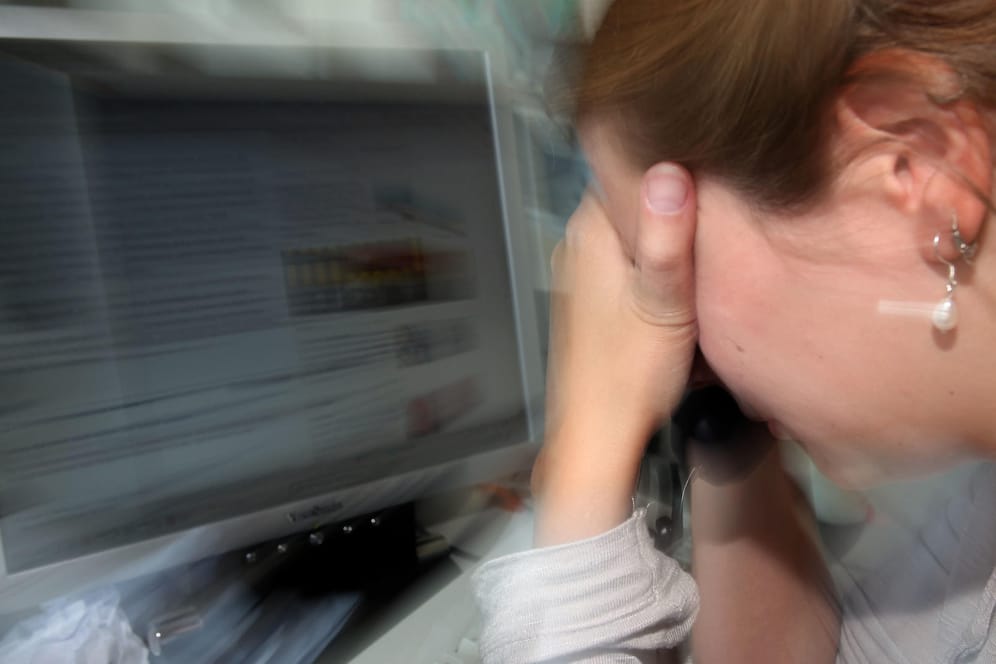Eine Frau legt an ihrem Arbeitsplatz den Kopf in die Hände: Grund können Augenprobleme wegen des Computerbildschirms sein.