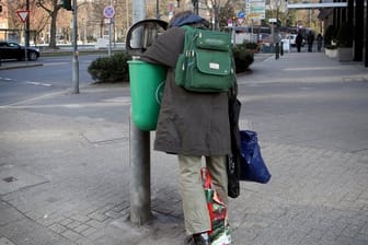 Ein Mann sucht in der Düsseldorfer Innenstadt in einem Mülleimer nach Verwertbarem.