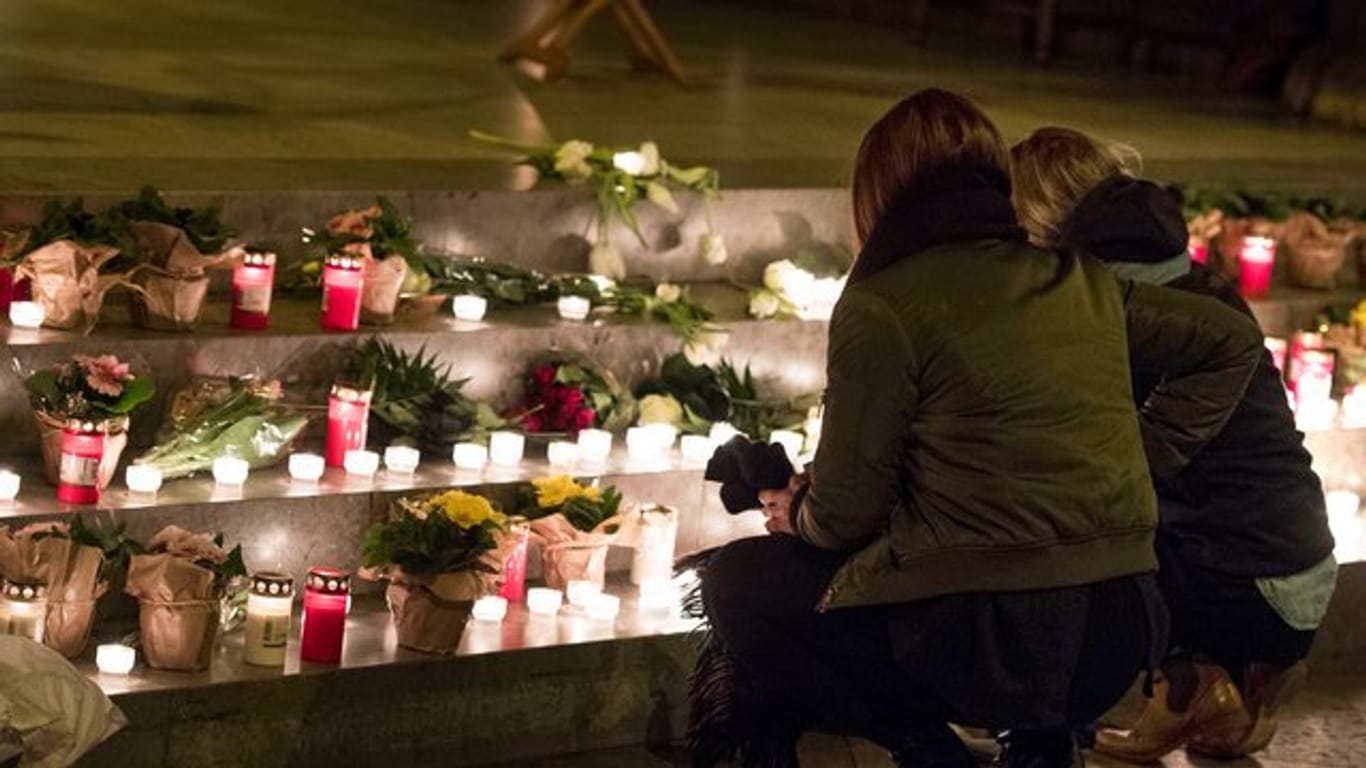 Zwei Frauen legen Blumen und Kerzen bei der Gedenkfeier für eine 17-Jährige in der Nikolaikirche auf die Stufen vor dem Altar.