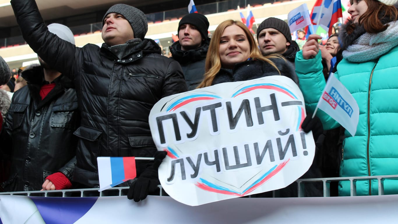 Die Studentin Jelena hält bei einer Wahlveranstaltung von Putin im Luschniki-Stadium ein Plakat in den Händen, auf dem "Putin ist der Beste" steht.