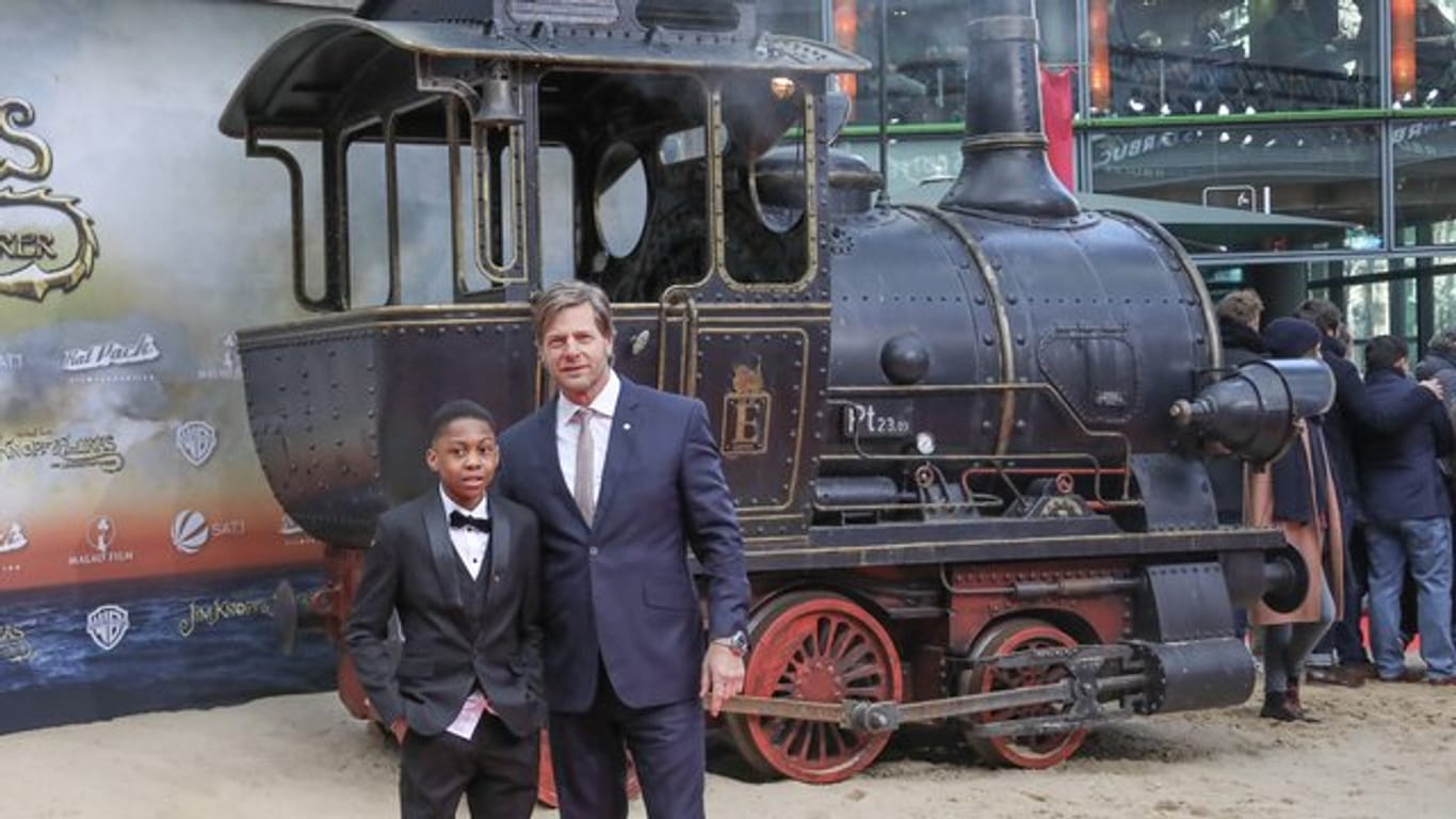 Die Schauspieler Solomon Gordon (l), Henning Baum und eine alte Dampflokomotive.