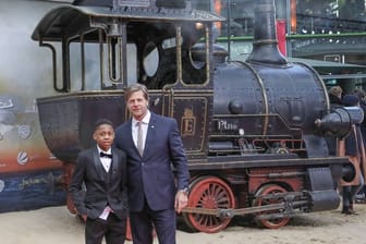 Die Schauspieler Solomon Gordon (l), Henning Baum und eine alte Dampflokomotive.