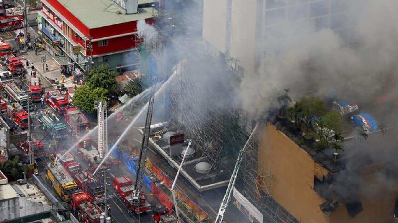 Feuerwehrleute kämpfen vor dem "Waterfront Manila Pavilion" gegen die Flammen.