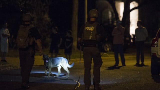 Polizisten mit Bombenspürhund am Ort der Explosion in Austin. Polizisten mit Bombenspürhund am Ort der Explosion in Austin.