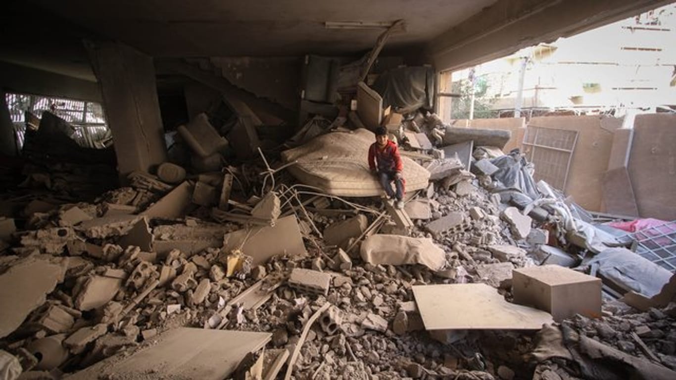 Ein Kind sitzt nach einem Luftangriff auf Duma in Ost-Ghuta nahe der syrischen Hauptstadt Damaskus auf einem Trümmerhaufen.