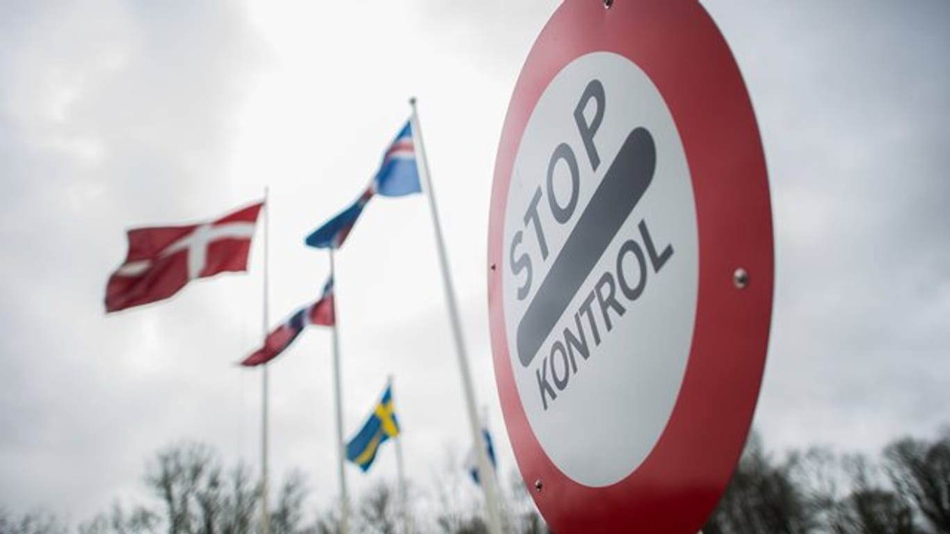 Auf einem Schild steht "Stop – Kontrol", im Hintergrund wehen Flaggen skandinavischer Ländern: Dänemark will einen Zaun an der deutsch-dänischen Grenze errichten lassen, um sich vor der Afrikanischen Schweinepest zu schützen.