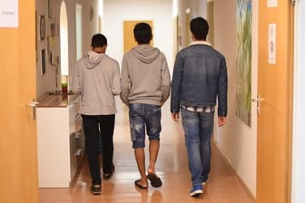Unbegleitete minderjährige Flüchtlinge gehen einen Flur entlang (Symbolbild): In Bremen soll die Aufteilung ausgewogener werden.