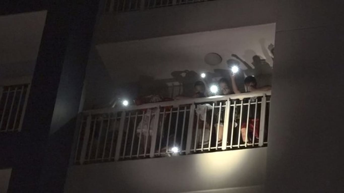 Bewohner eines Wohnkomplexes rufen mit den Lichtern ihrer Mobiltelefone um Hilfe nach dem Ausbruch eines Feuers.