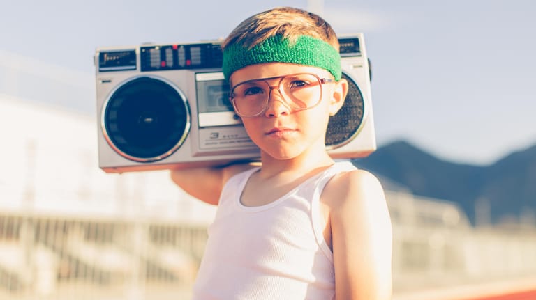 Ein Junge mit Stirnband und Brille hat ein Radio auf den Schultern