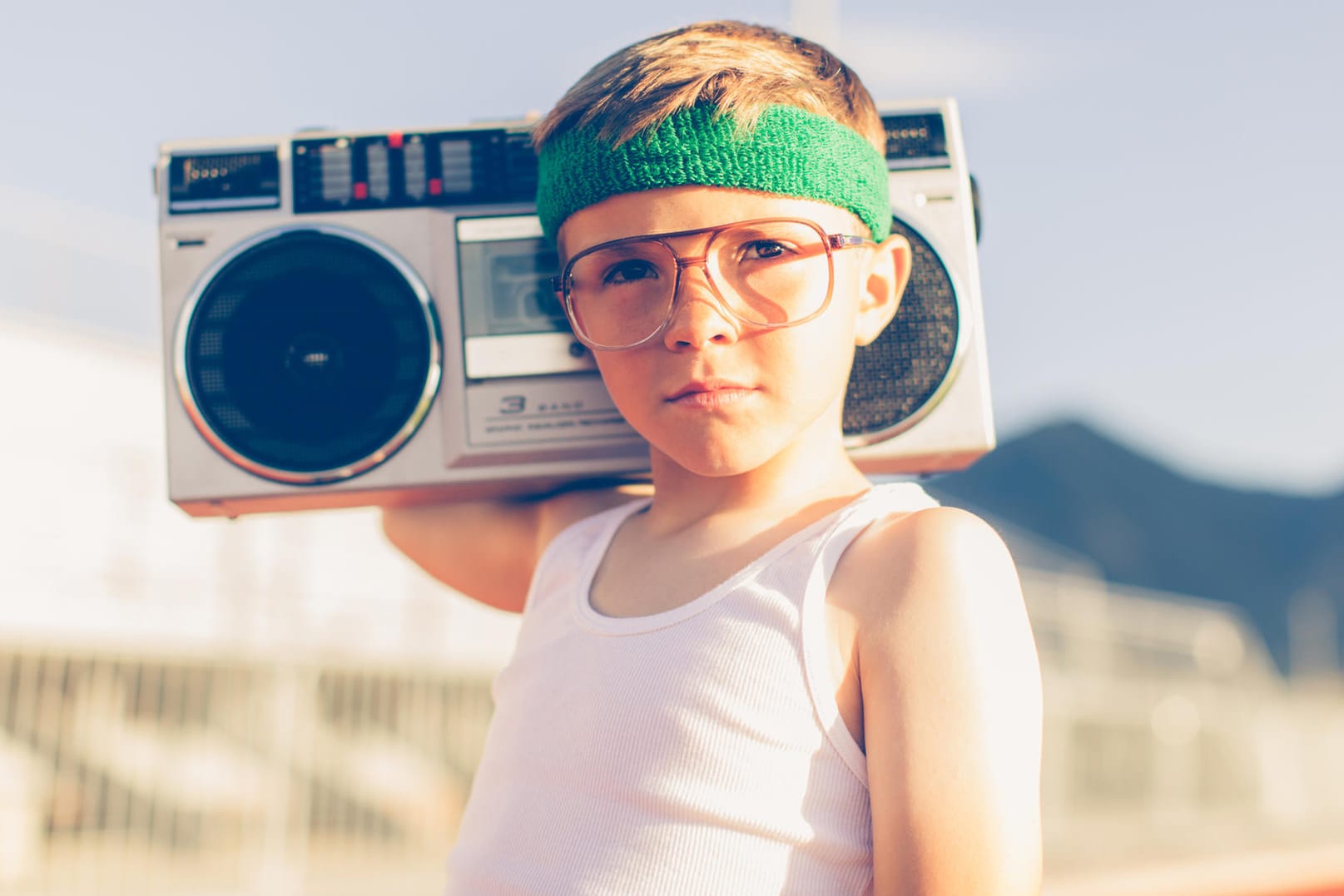 Ein Junge mit Stirnband und Brille hat ein Radio auf den Schultern