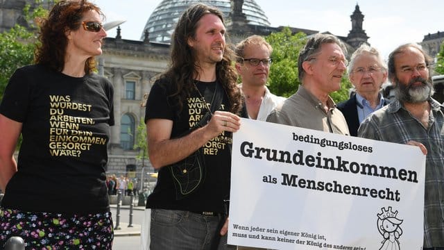 Mitglieder der Bürgerinitiative "Omnibus" werben im Mai 2015 vor dem Reichstag für eine Volksabstimmung zum bedingungslosen Grundeinkommen. Mitglieder der Bürgerinitiative "Omnibus" werben im Mai 2015 vor dem Reichstag für eine Volksabstimmung zum bedingungslosen Grundeinkommen.