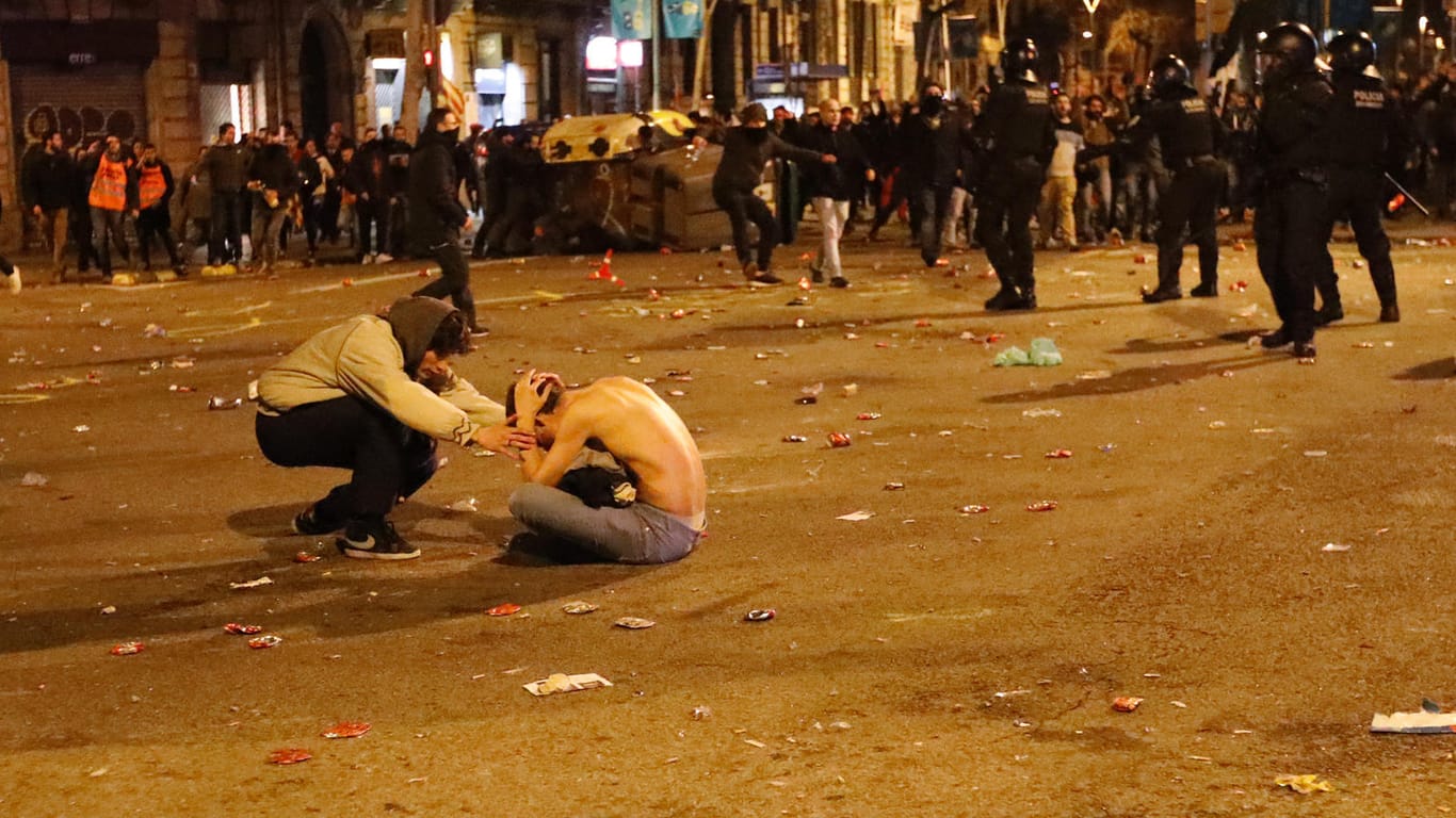 Ein Mann sitzt während eines Protests gegen die Inhaftierung des ehemaligen Regionalpräsidenten Kataloniens, Puigdemont, auf der Straße und hält sich den Kopf: Am Rande einer Demonstration von mehr als 50.000 Menschen in Barcelona haben Polizeibeamte auch Warnschüsse in die Luft abgegeben.