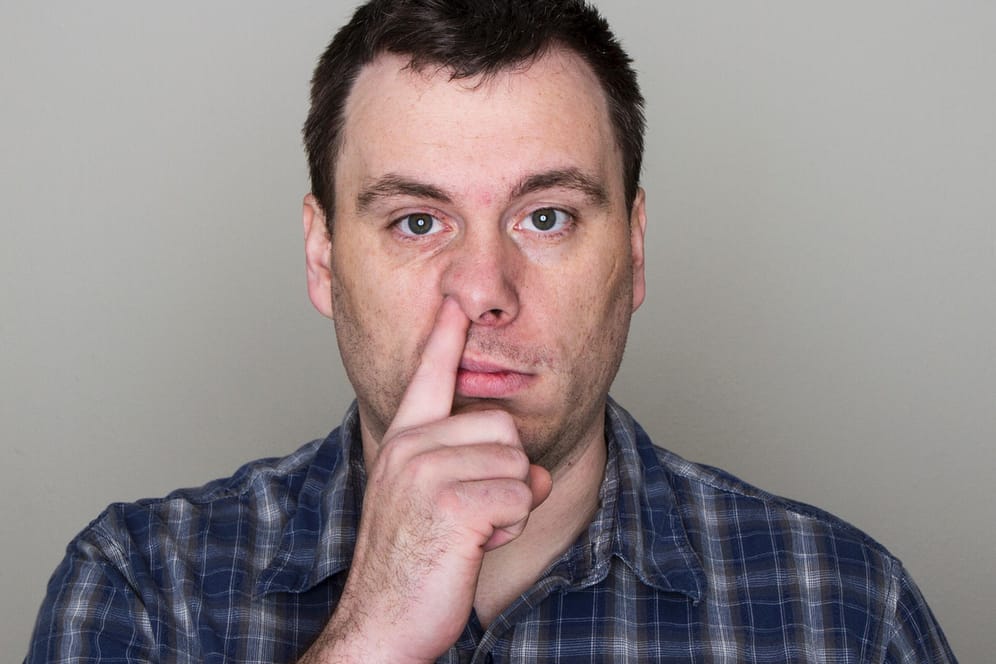 Mann bohrt in der Nase: Eine gesunde Nase steckt nicht ständig voller Popel.
