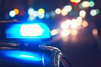 Polizeiauto mit Blaulicht nachts auf einer Straße: Die Polizisten fanden den 16-Jährigen auf dem Boden liegend mit einer Wodkaflasche.