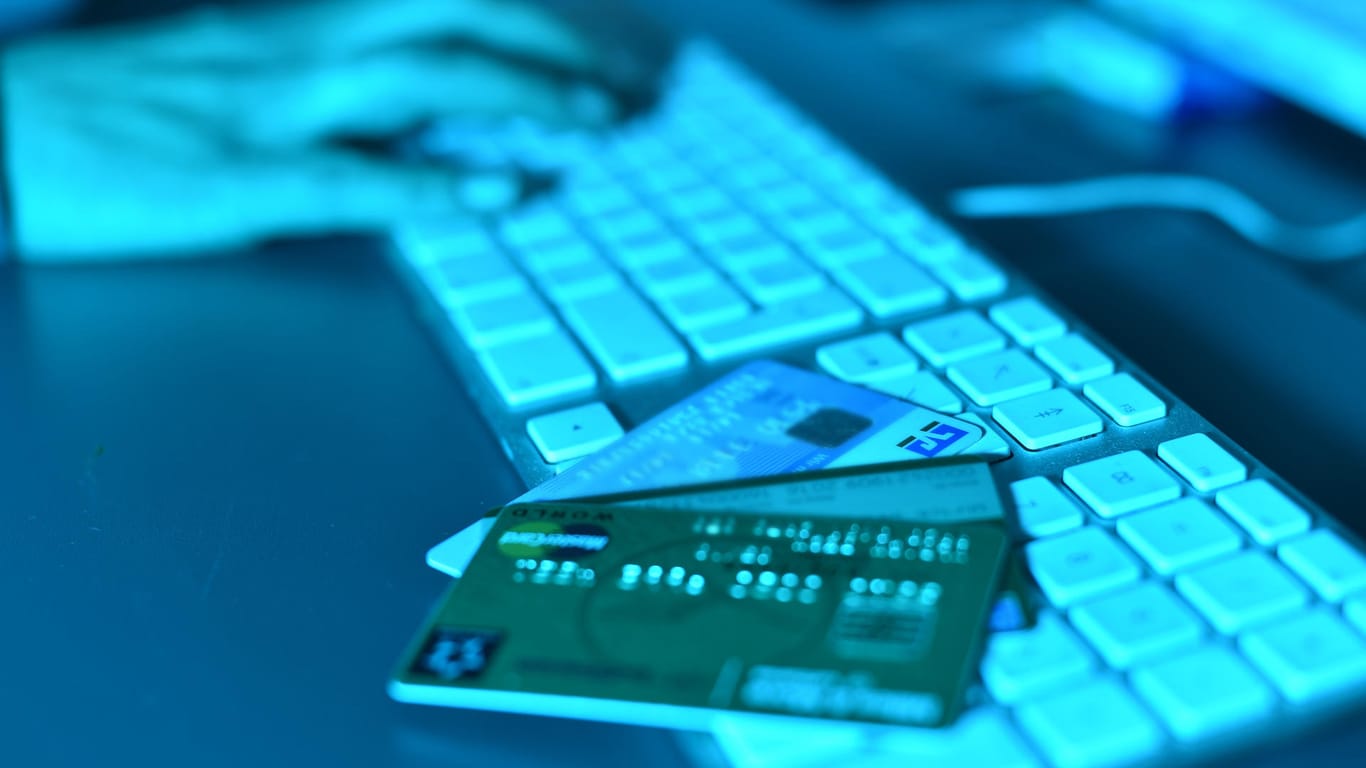 Auf einer Computertastatur liegen am Kreditkarten: Kopf von Internetbetrüger-Bande festgenommen.