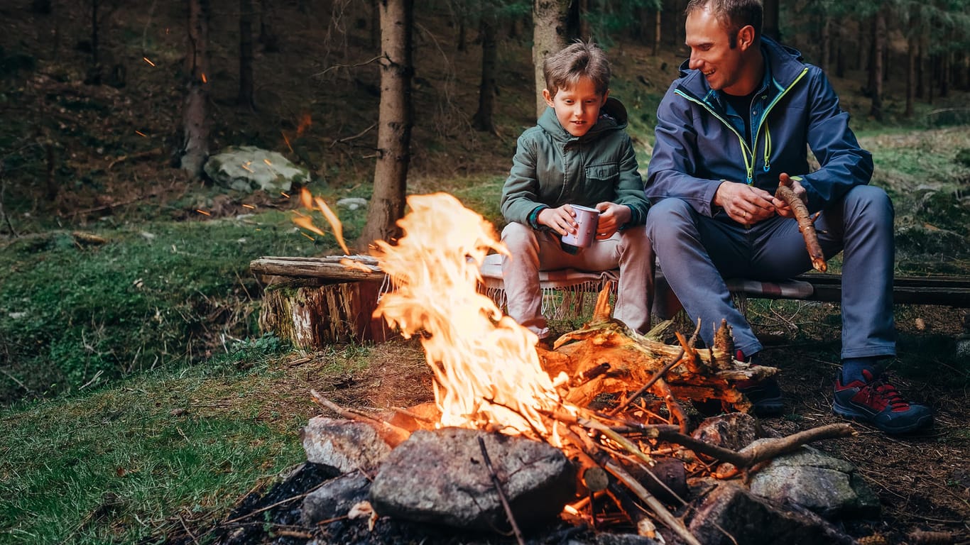 Vater und Sohn am Lagerfeuer: Ein Feuer muss generell ständig beaufsichtigt werden.