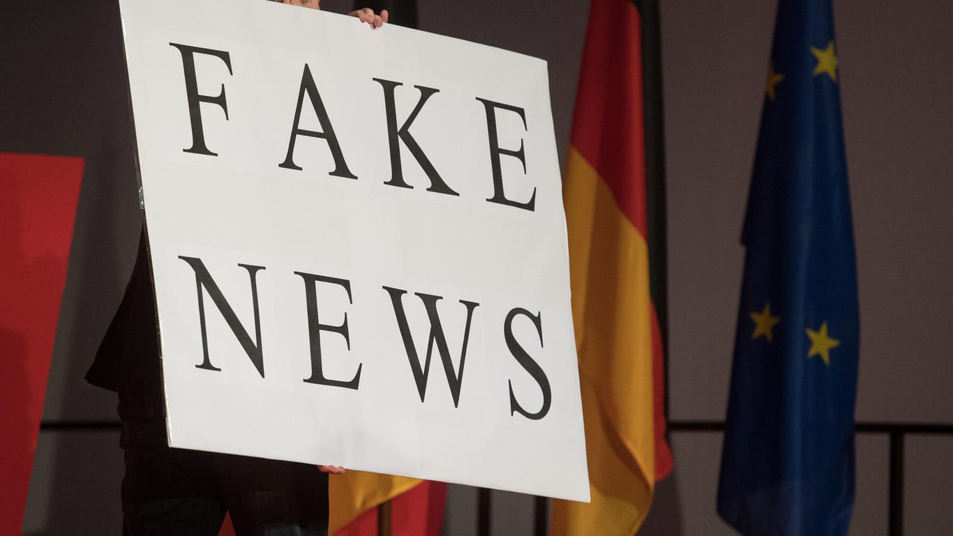 Oft nicht so offensichtlich: Ein Mann trägt ein Schild mit der Aufschrift "Fake News". Eine Studie analysiert, wie groß solche Meldungen vor der Bundestagswahl herausgekommen sind.