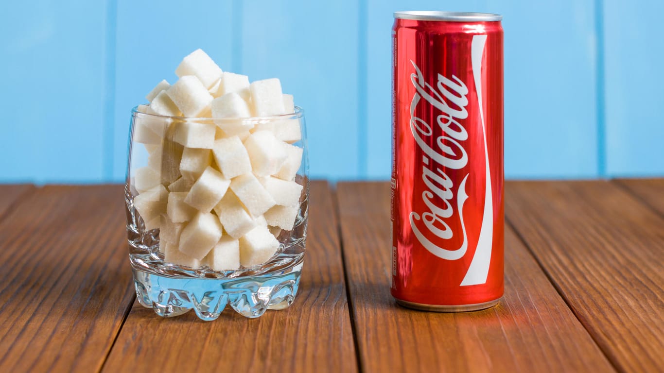 Eine Dose Coca-Cola neben einem Glas Zucker