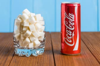 Eine Dose Coca-Cola neben einem Glas Zucker
