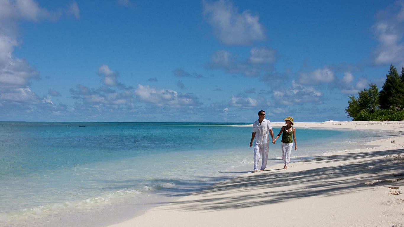 Ein Paar am Strand: Reiseveranstalter locken Urlauber jetzt mit neuen Zahlungsmöglichkeiten.