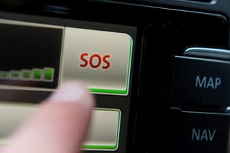 Schriftzug "SOS" ist auf dem Display eines Bordcomputers mit Touchpad eines Volkswagen Fahrzeuges: Kommt es zum Unfall, erkennen Beschleunigungssensoren im Stecker die Schwere der Kollision und melden den Unfall via Smartphone an eine Notrufzentrale.