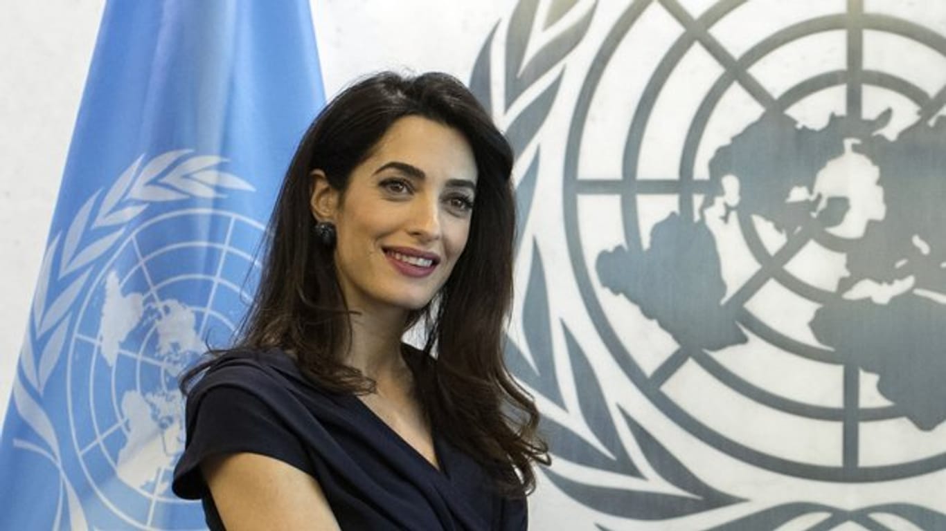 Rechtsanwältin Amal Clooney vor dem Logo und der Fahne der UN.