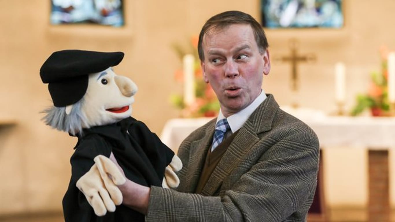 Pastor Jörg Mosig in der Alt Hastedter Kirche mit einer Puppe, die Martin Luther darstellen soll.