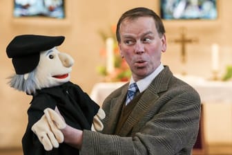 Pastor Jörg Mosig in der Alt Hastedter Kirche mit einer Puppe, die Martin Luther darstellen soll.