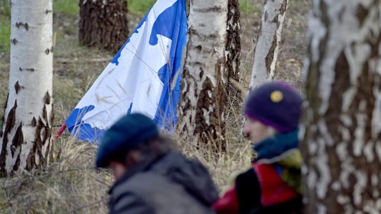 Eine Fahne mit einer Friedenstaube lehnt beim Ostermarsch 2018 in Gronau vor der Uran-Anreicherungsanlage Urenco an einem Baum.