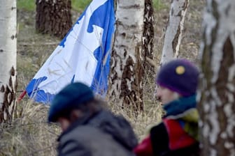 Eine Fahne mit einer Friedenstaube lehnt beim Ostermarsch 2018 in Gronau vor der Uran-Anreicherungsanlage Urenco an einem Baum.