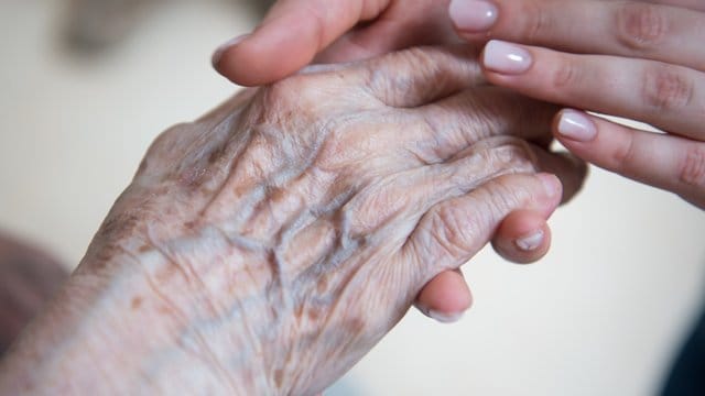 Eine Pflegerin hält die Hand einer Bewohnerin eines Seniorenzentrums. Eine Pflegerin hält die Hand einer Bewohnerin eines Seniorenzentrums.