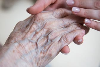 Eine Pflegerin hält die Hand einer Bewohnerin eines Seniorenzentrums.