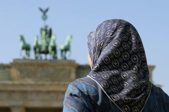 Eine muslimische Frau mit Kopftuch vor dem Brandenburger Tor in Berlin.