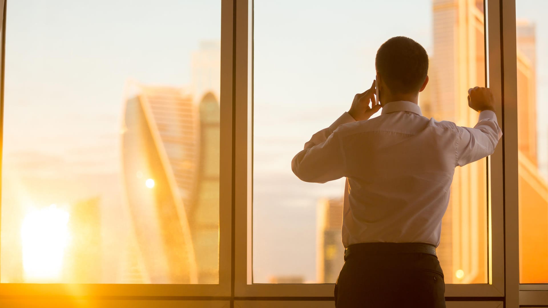 Telefonierender Geschäftsmann am Fenster