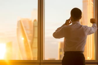 Telefonierender Geschäftsmann am Fenster