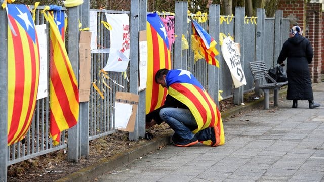 Ein Mann befestigt am Zaun vor der Justizvollzugsanstalt eine Estelada, die Fahne der katalanischen Nationalisten.