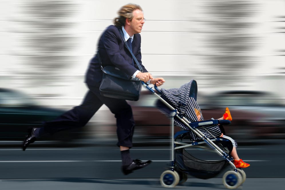Geschäftsmann rennt mit Kinderwagen.