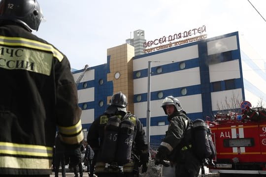 Feuerwehrleute stehen vor dem Einkaufszentrum "Persej dlja detej" (Perseus für Kinder), in dem ein Feuer ausgebrochen ist.